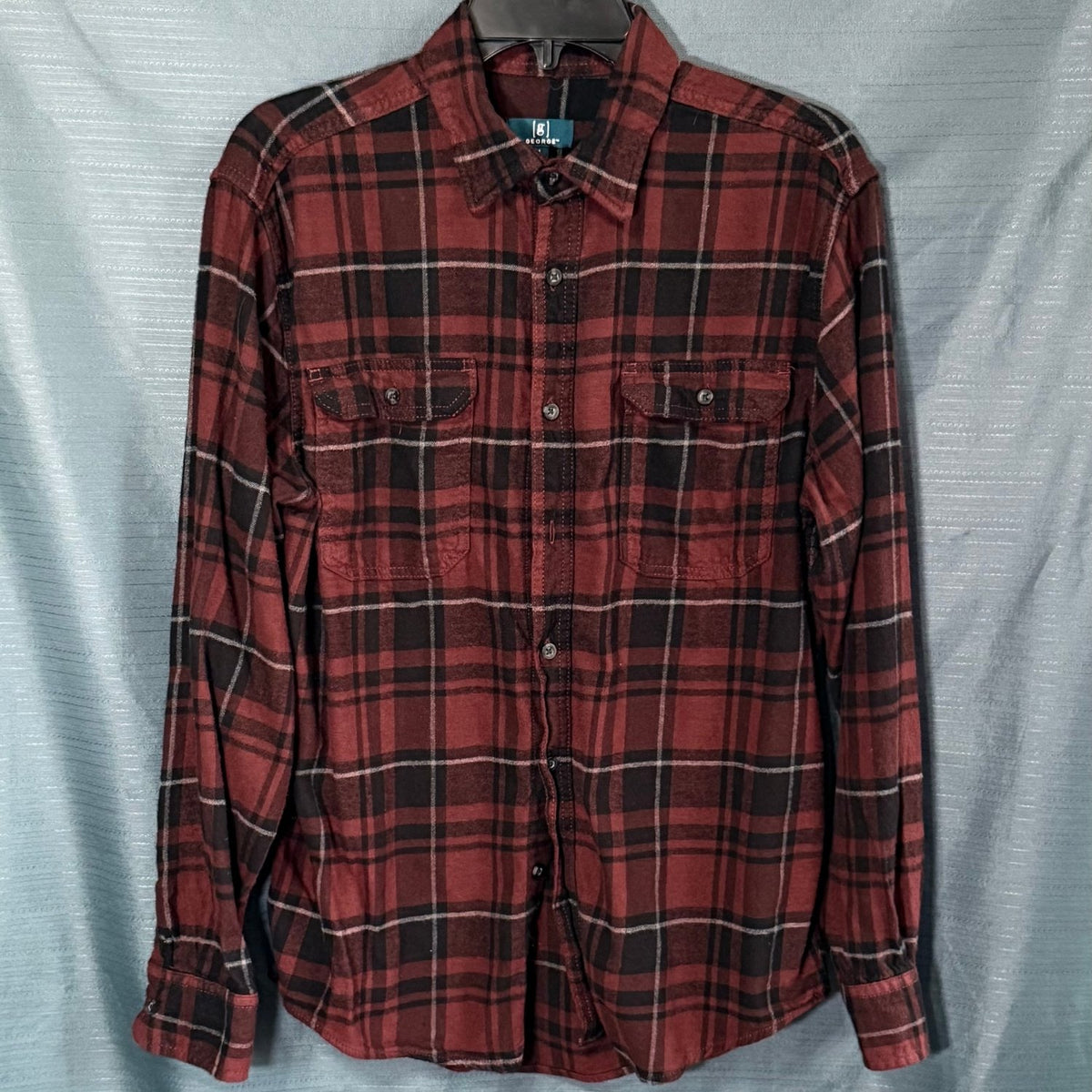Front view of George men's medium burgundy and black plaid button-up flannel shirt with two button-flap chest pockets and long sleeves.