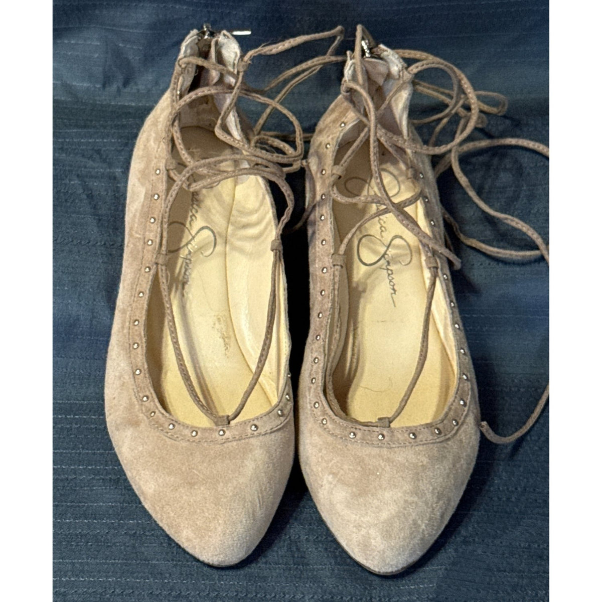 Front view of tan Jessica Simpson ballet flats with rounded toes, lace-up ties, and metallic stud trim.