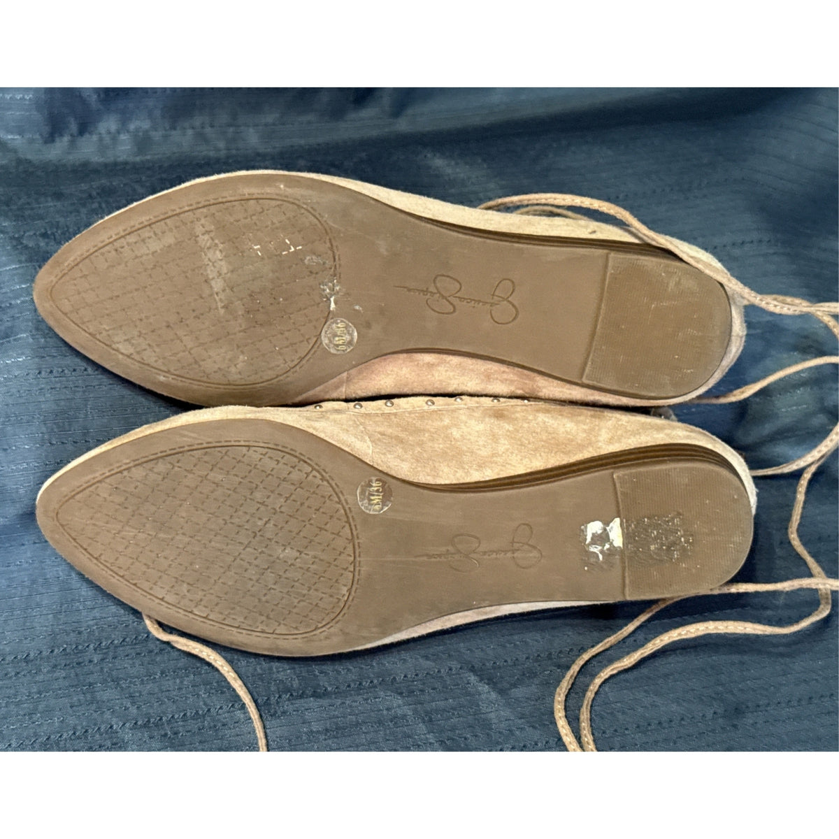 Soles of tan Jessica Simpson ballet flats showing tread, low heels, and visible wear.
