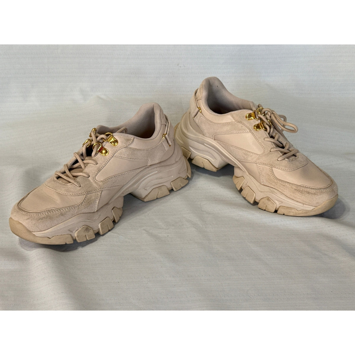 Angled overhead view of JustFab Ximena sneakers showing padded collars, beige laces, and gold-tone hardware.
