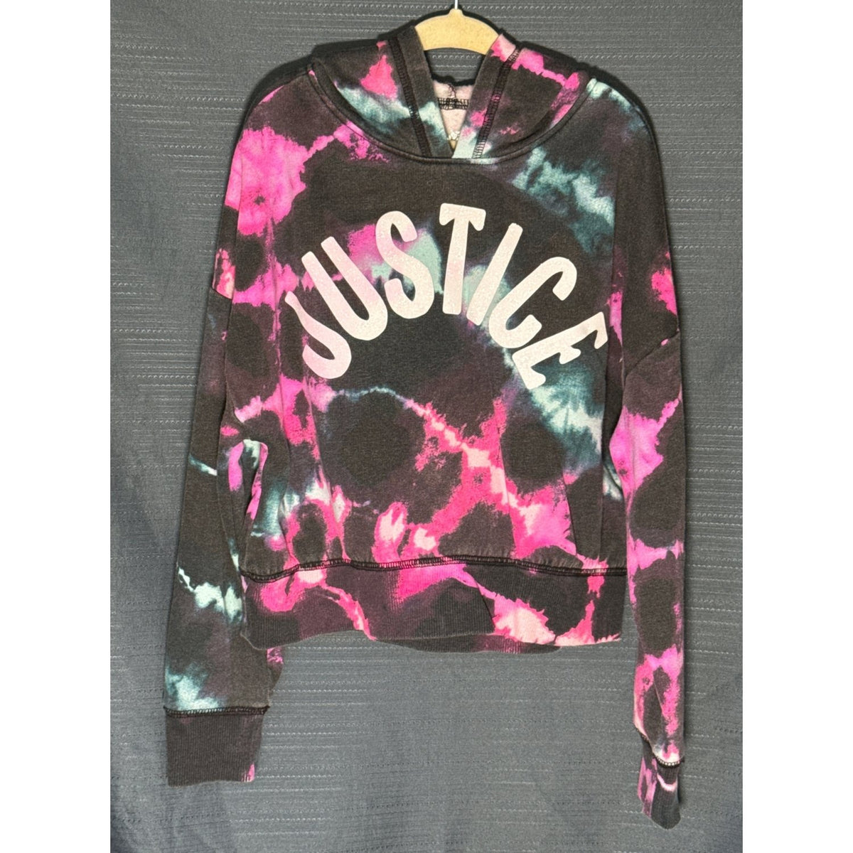 Front view of Justice girls' XS 5/6 cropped tie-dye hoodie with sparkly JUSTICE lettering, pink and blue accents, and long sleeves.