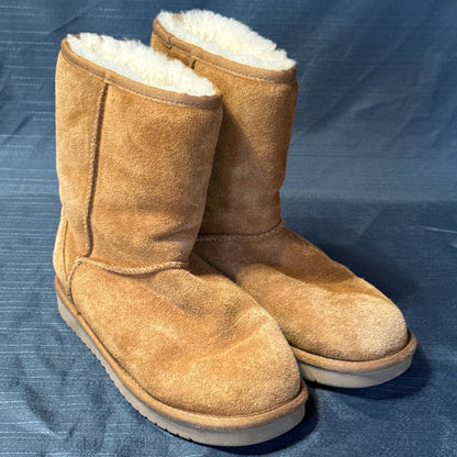 Opposite angled view of chestnut suede short boots showing rounded toes, stitching, and plush lining.