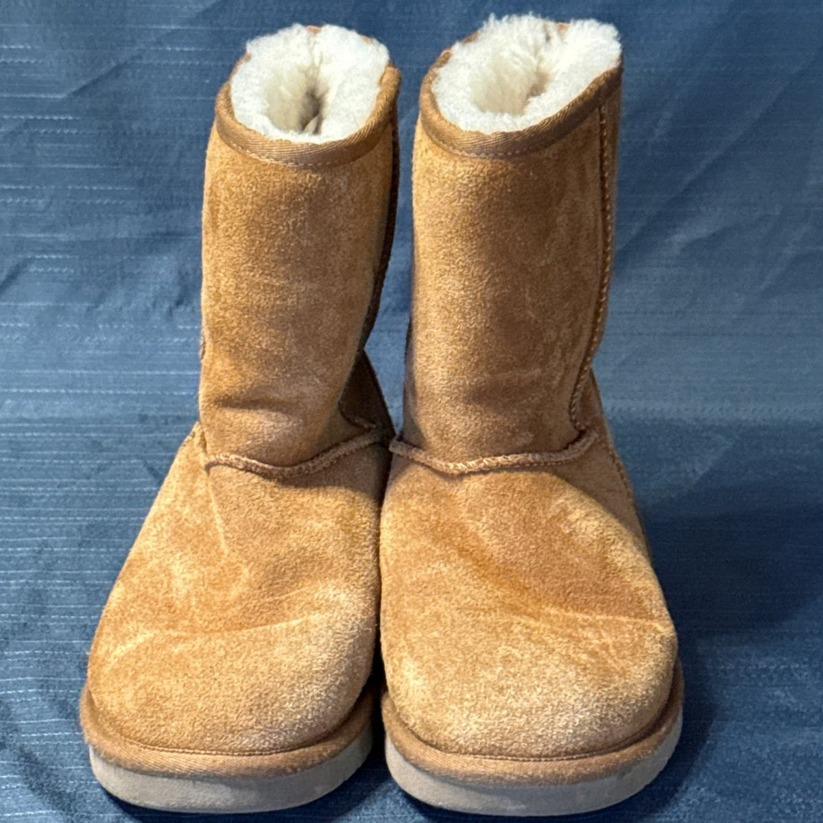 Straight-on front view of chestnut suede boots with rounded toes and cream-colored lining.