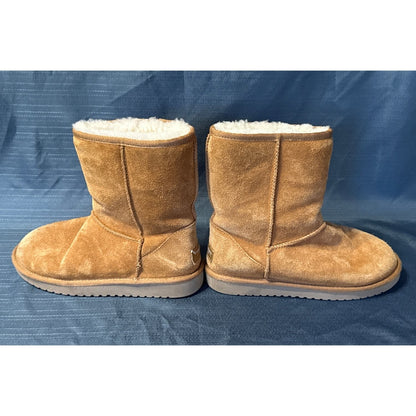 Inner side view of chestnut suede short boots showing exposed seams and flat soles.