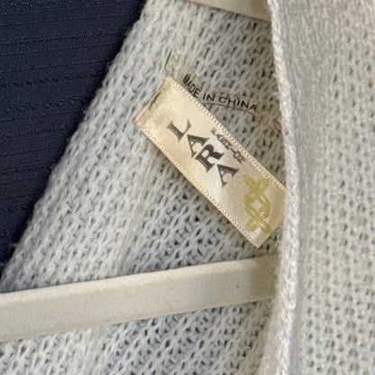 Close-up of the Lara Fashion brand tag on an ivory knit sweater.