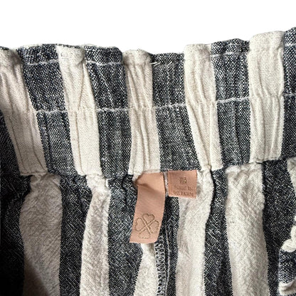 Pink clothing tag with clover leaf gold stitching on striped linen pants