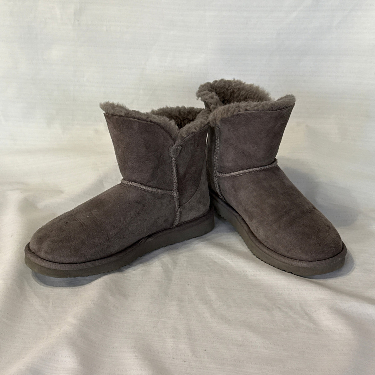 Angled front view of Member's Mark gray suede short boots showing rounded toes, exposed seams, and fluffy sheepskin lining.