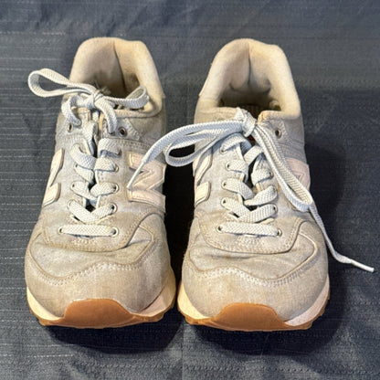 Front view of light blue New Balance 574 lace-up sneakers showing rounded toes and visible discoloration.