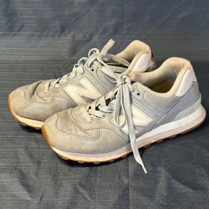 Left-side view of light blue New Balance 574 sneakers with white N logos and gum-colored outsoles.