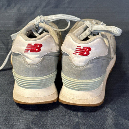 Back view of New Balance 574 sneakers showing white heel panels with red embroidered logos.