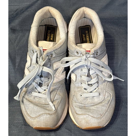 Top view of New Balance 574 sneakers showing blue laces, padded collars, insoles, and discoloration.
