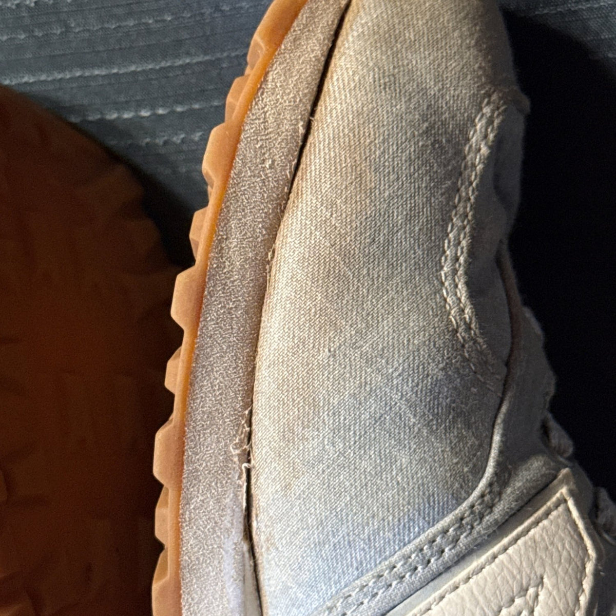 Close-up showing separation between the fabric upper and sole along the inner side of one sneaker.