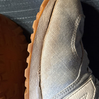 Close-up showing separation between the fabric upper and sole along the inner side of one sneaker.