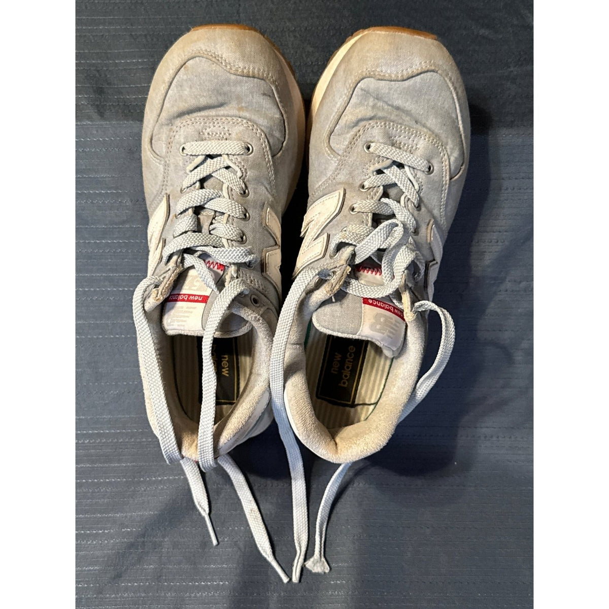 Top view of light blue New Balance 574 sneakers showing laces, visible wear, and discoloration.