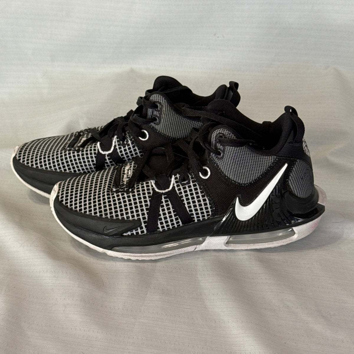 Side view of black and white Nike LeBron Witness 7 basketball sneakers with white Swoosh and visible heel cushioning.