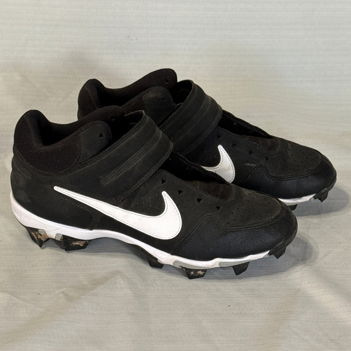 Right-facing angled view of Nike baseball cleats showing white Swooshes, perforated uppers, and molded studs.