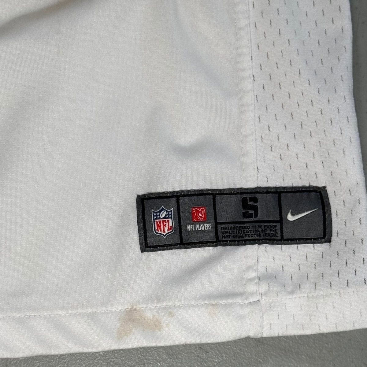 Nike NFL On Field hem label and visible discoloration on white youth jersey