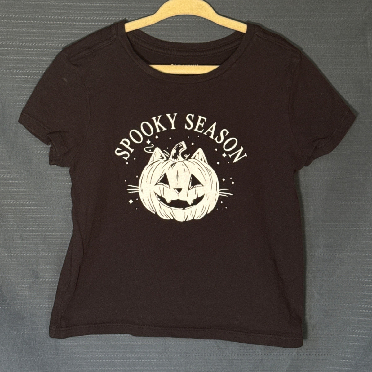 Old Navy girls black Halloween graphic T-shirt featuring white Spooky Season lettering and cat-faced jack-o'-lantern illustration, size 6–7.