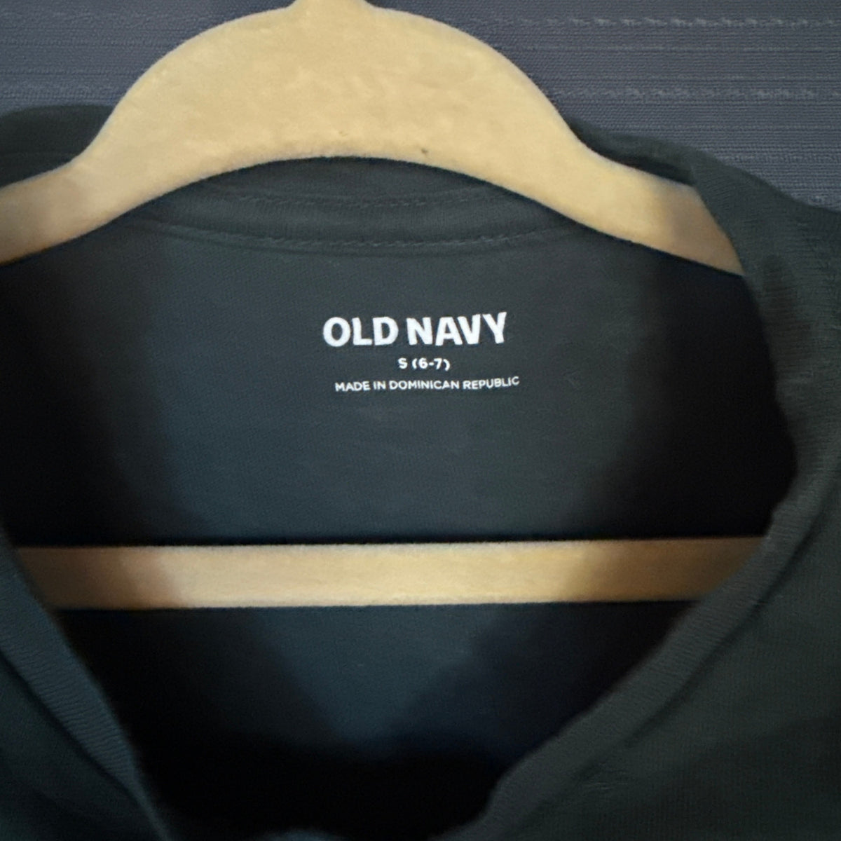 Old Navy girls clothing label showing size Small 6–7 inside muted teal green T-shirt.