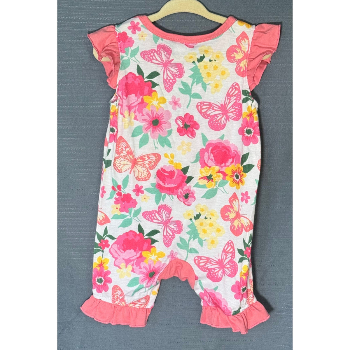 Back view of PatPat baby girls romper size 9–12 months with colorful floral and butterfly print, coral-pink ruffled sleeves and leg hems.