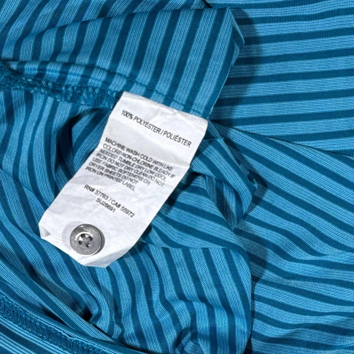 Close-up of the blue striped pattern, black collar, and button placket on the PGA TOUR performance golf polo.