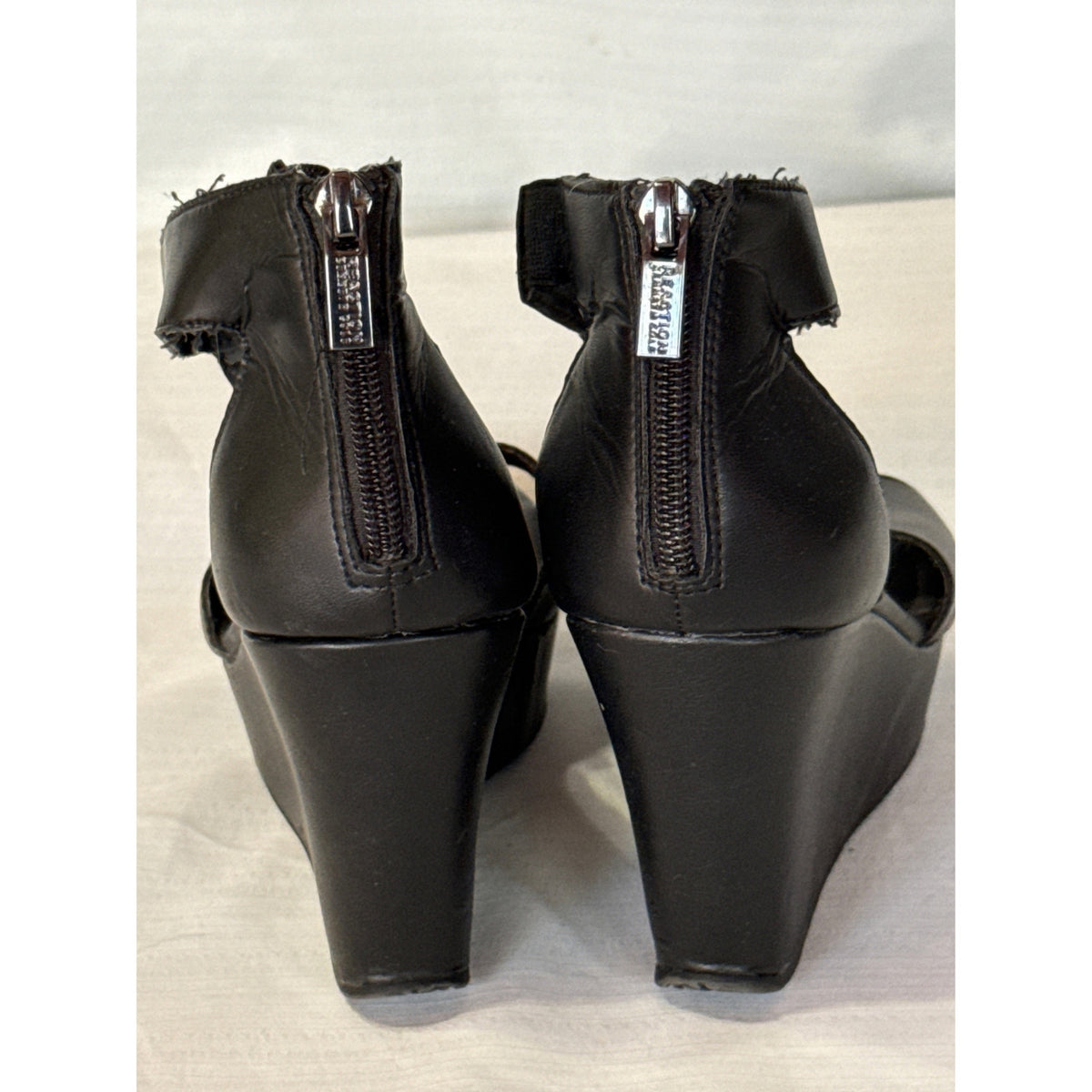 Back view of black Reaction Kenneth Cole wedge sandals showing silver zipper closures and ankle cuff wear.