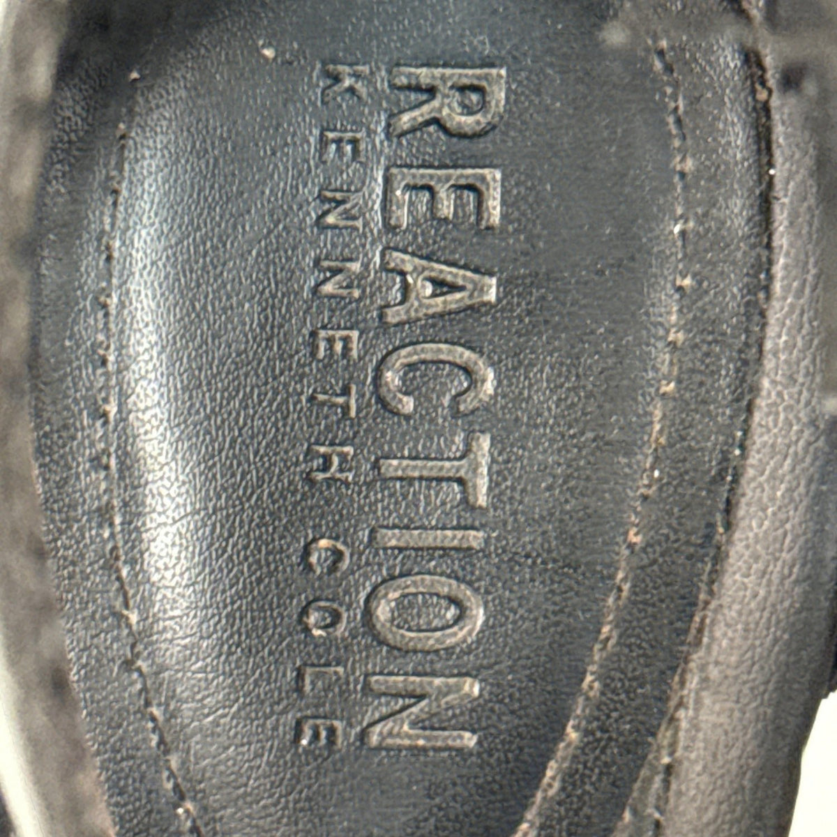 Close-up of Reaction Kenneth Cole branding on the black sandal footbed.