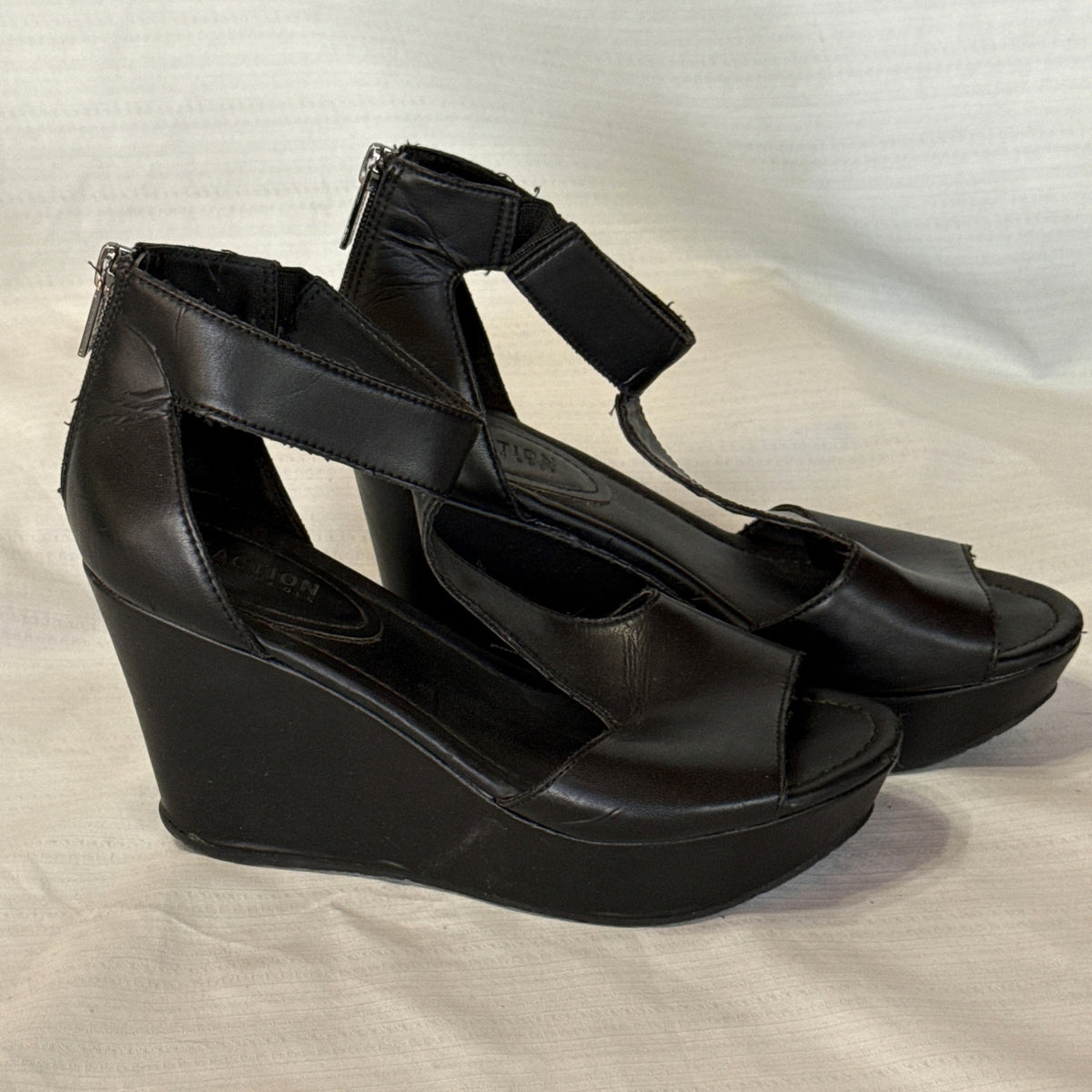 Angled side view of black Reaction Kenneth Cole wedge sandals with open toes and ankle straps.