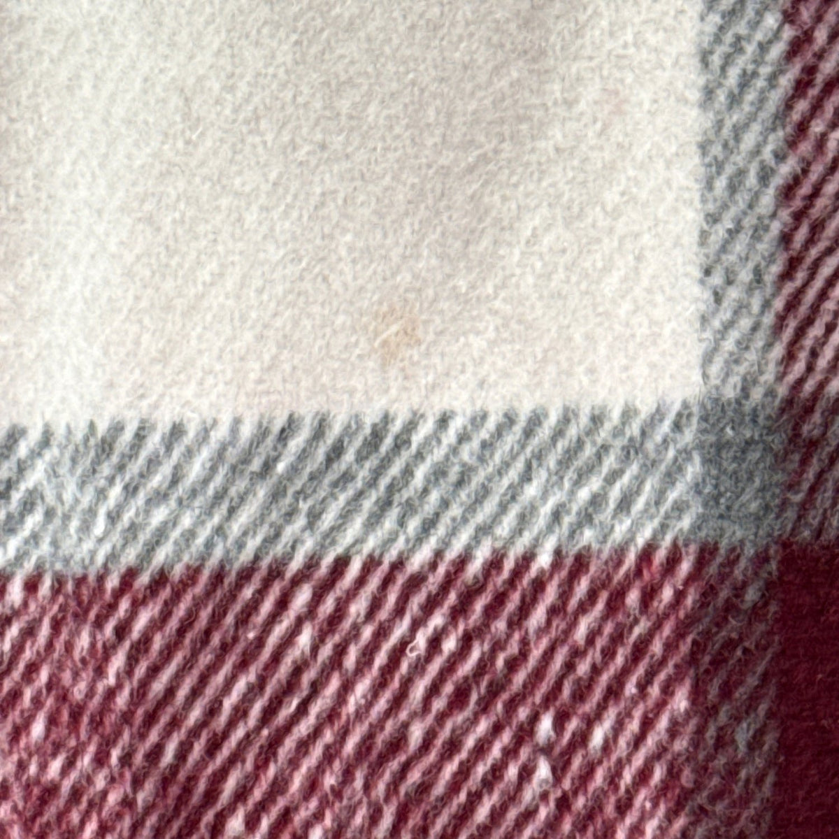 Close-up of small light stain on lower back of SHEIN plaid cardigan