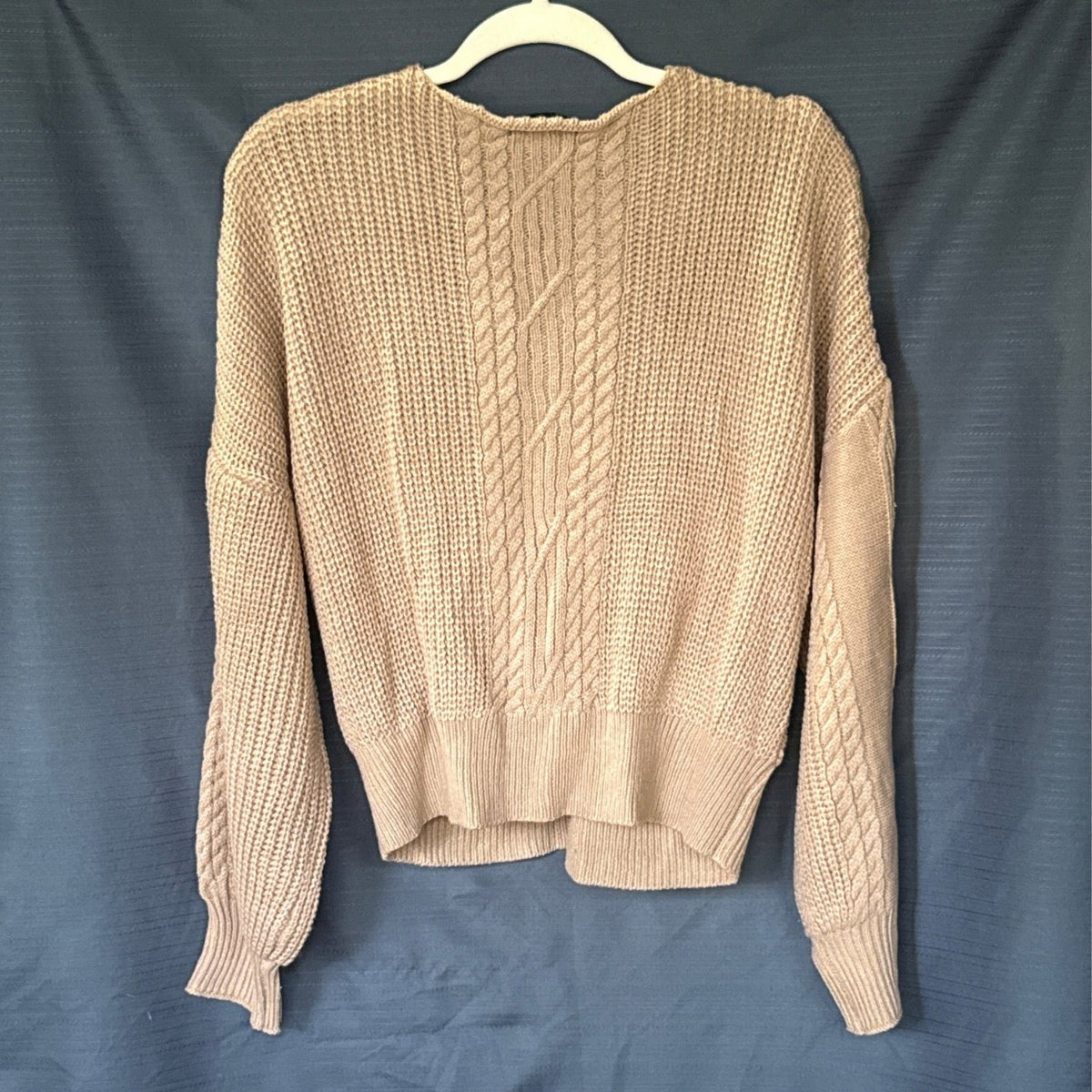 Back of a beige SHEIN women’s sweater with a central cable-knit panel, long sleeves, and ribbed hem and cuffs.