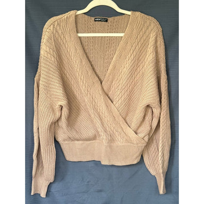 Front of a beige SHEIN women’s sweater with a crossover V-neckline, cable-knit details, and dropped shoulders.