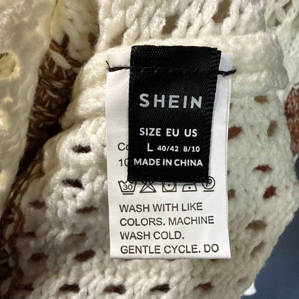 SHEIN sweater label showing size large, EU 40/42, and US 8/10 against cream and brown knit fabric.