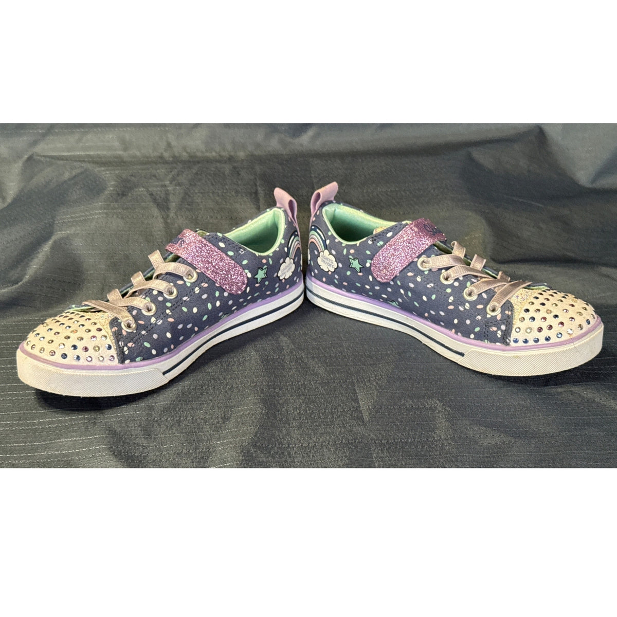 Inner-side view of Skechers Twinkle Toes sneakers showing pastel sprinkle designs, stretchy laces, and light on-off markings.
