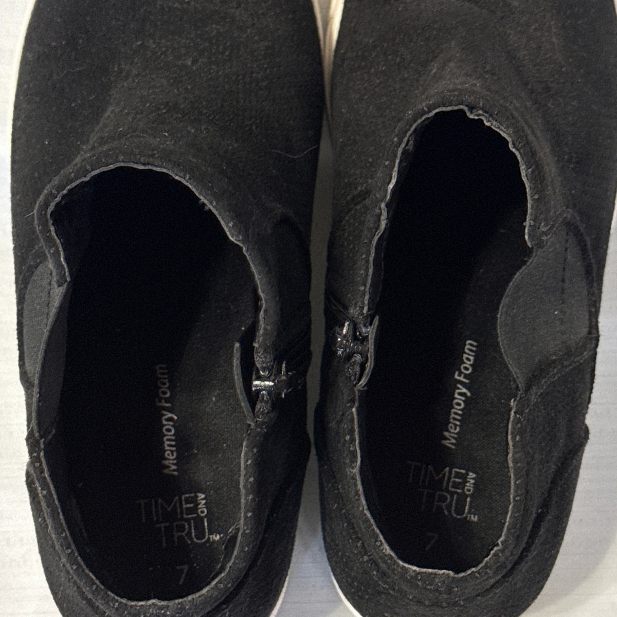 Interior view of black Time and Tru sneaker booties showing memory foam branding, size 7, and side zippers.
