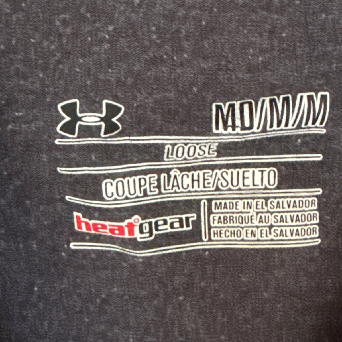 Under Armour printed neckline label showing Medium, Loose fit, HeatGear, and made in El Salvador