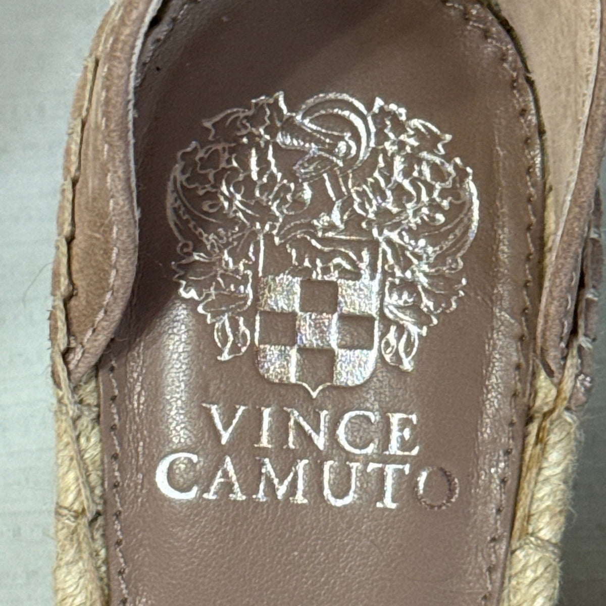 Close-up of Vince Camuto brand name and crest printed on the brown sandal footbed.