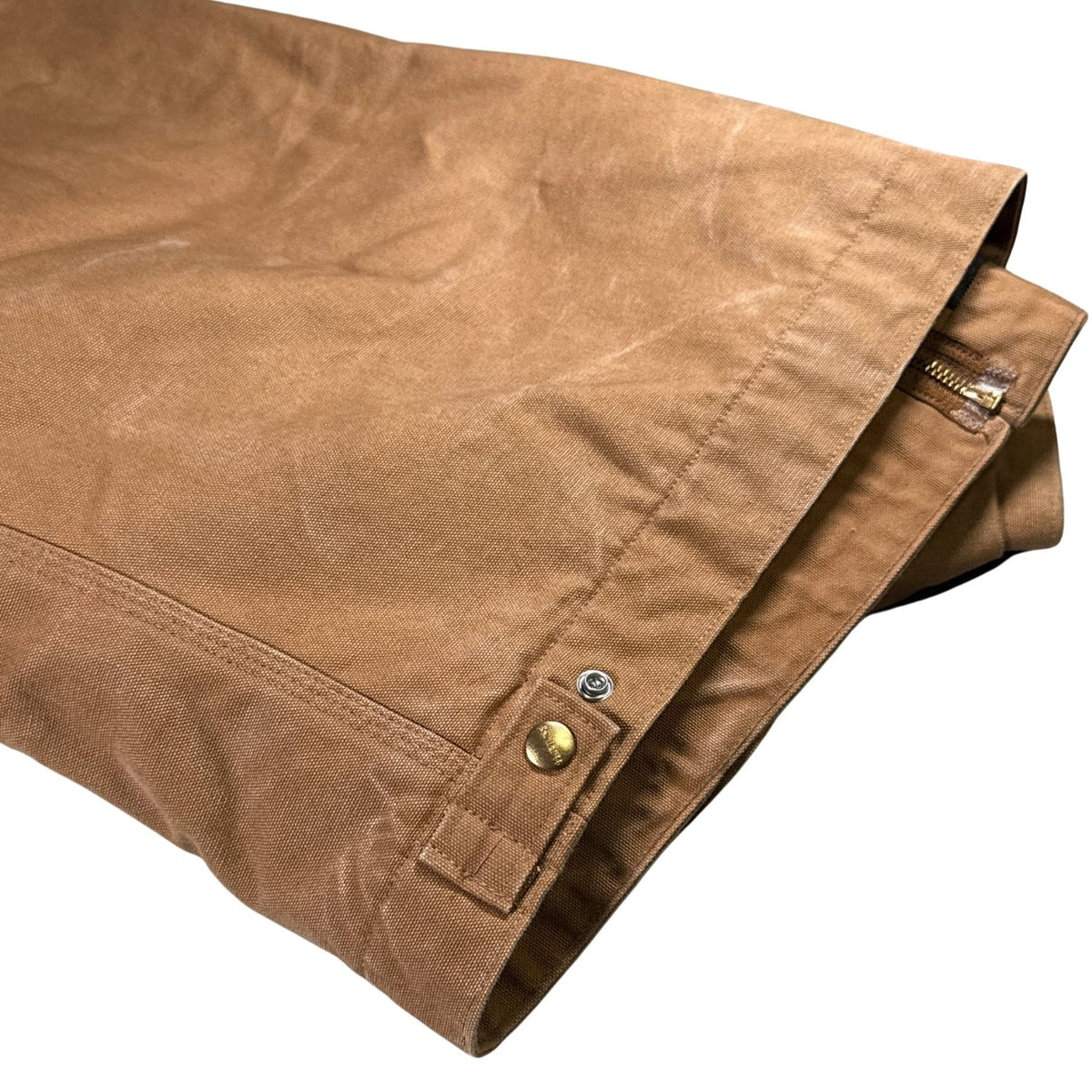 Close-up of hem seams and snap-adjustable waist tabs on vintage Carhartt Detroit Jacket