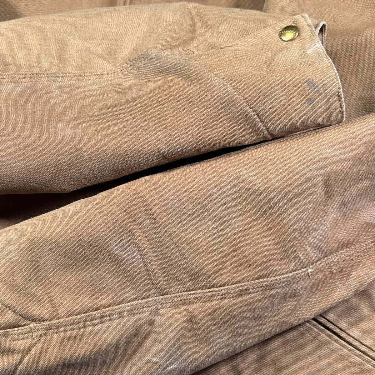 Close-up of small dark marks on the underside of the right forearm near the cuff of vintage Carhartt jacket