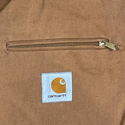 Close-up of zippered chest pocket and woven Carhartt logo on brown duck Detroit Jacket
