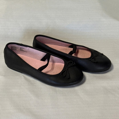 Right angled view of black Wonder Nation ballet flats showing toe bows, elastic instep straps, and pink lining.
